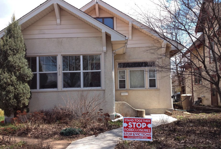 This image is of a house with a sign on its yard reading "stand together stop foreclosures stop evictions" 