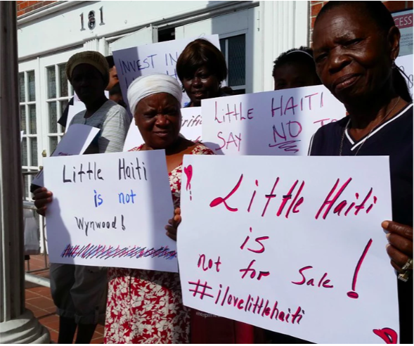 Haitian women holding signs that read "little haiti is not for sale!"